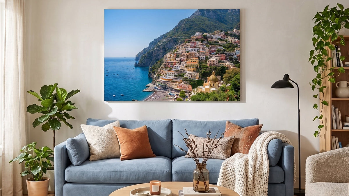 Large canvas print of a colourful seaside town above a blue sofa in a bright living room
