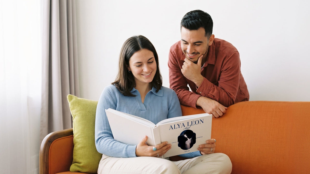 Couple looking through a personalised anniversary photo book together on a sofa